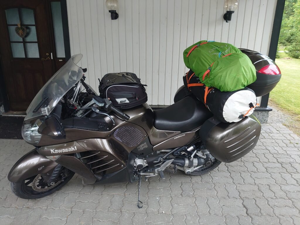 Packed Kawasaki GTR 1400 motorcycle ready for a long journey, loaded with multiple bags and gear packages.